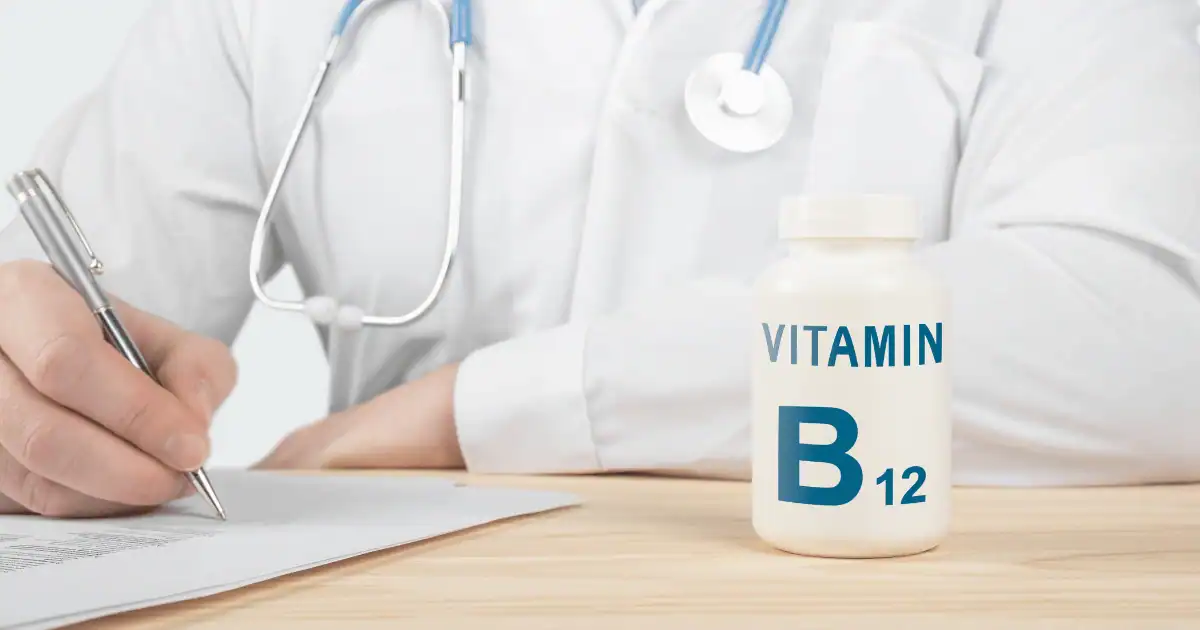 A doctor in a white coat sitting at a desk writing a prescription for vitamin B12