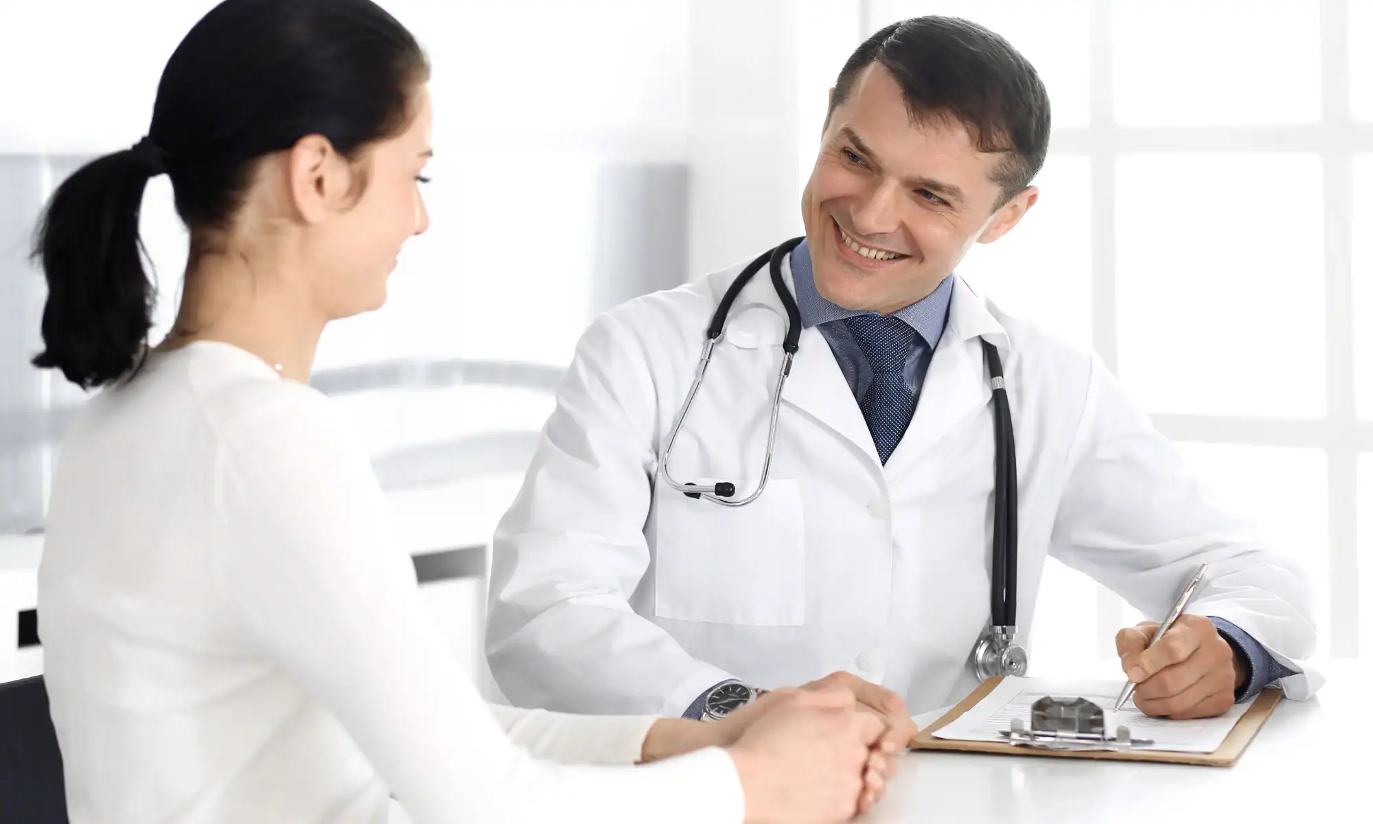 Doctor and patient discussing glp-1 options at a medical weight loss clinic in Oklahoma. Physician using clipboard for filling up medication history records.