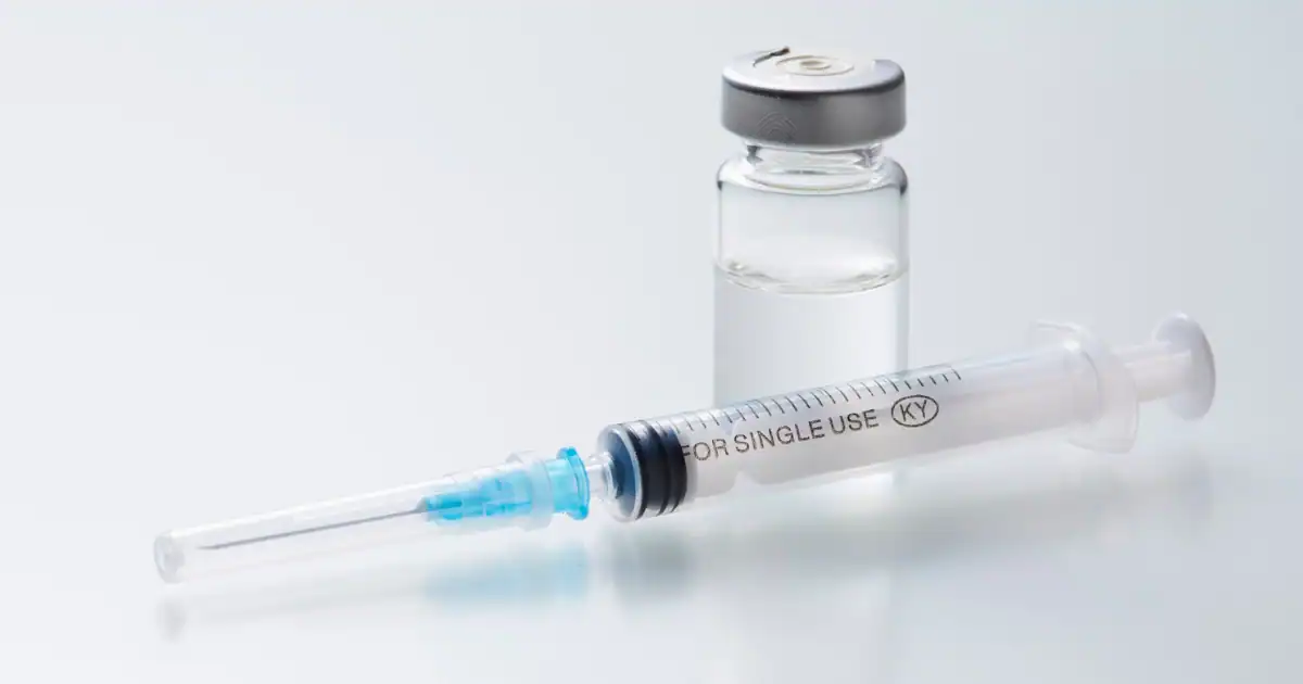 Clear medical syringe labeled "FOR SINGLE USE" placed beside a small vial of liquid medication on a white background representing injectable treatments sometimes used in weight loss services in Tulsa.