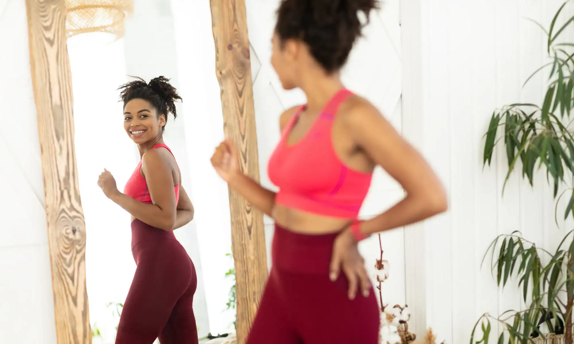 Joyful African woman after successfully losing weight at Slim Care lookin in the mirror