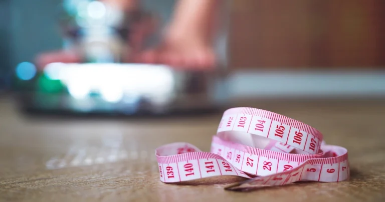 Pink measuring tape on a wooden surface representing weight management for an article explaining what tirzepatide is.